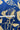 A close-up of a blue fabric with a beige botanical leaf pattern, with a white measuring tape laid horizontally across the middle to indicate scale.