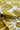 A close-up of draped fabric with a bold tropical leaf pattern in olive green and white.