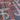 A close-up of a fabric surface with a geometric abstract pattern featuring white, orange, and pink lines on a dark gray background.