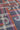 A close-up of a fabric surface with a geometric abstract pattern featuring white, orange, and pink lines on a dark gray background.