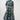 A woman modeling a short-sleeve midi shirt dress with a colorful abstract geometric print on a dark teal background, 