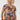 A woman with curly blonde hair wearing a short-sleeve scoop-neck top with an orange and gray abstract circular pattern on a dark teal background, 