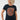 A woman with curly blonde hair wearing a navy blue short-sleeve t-shirt with a large circular orange and gray graphic on the chest, 