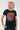 A woman with curly blonde hair wearing a navy blue short-sleeve t-shirt with a large circular orange and gray graphic on the chest, 
