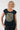 A smiling woman with curly blonde hair wearing a navy blue scoop-neck t-shirt with a large olive green and white sunburst graphic on the front, 
