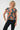 A woman modeling a short-sleeve top with a teal blue-green base and a large orange and light gray abstract floral pattern, 