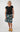 A woman modeling a black short-sleeve top and a knee-length skirt with a colorful geometric pattern 