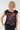A smiling blonde woman wearing a navy blue scoop-neck t-shirt with a rust-orange abstract pattern 