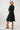 A woman modeling a black short-sleeve A-line dress from the back,