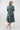 A woman viewed from behind wearing a dark teal midi dress with a colorful retro pattern 