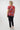 A woman viewed from the back wearing a red short-sleeve t-shirt with a colorful abstract geometric pattern, 