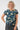 wearing a short-sleeve crewneck top with a multicolor abstract pattern on a dark teal background, 