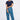 A woman modeling a pair of blue patterned pants with a navy t-shirt and navy sneakers, 
