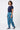 A woman modeling a pair of blue patterned pants with a navy t-shirt and navy sneakers, 