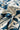 A close-up of a draped fabric with a bold, dark teal blue abstract floral and leaf pattern on an off-white background.