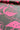 A close-up of a patterned fabric or wallpaper featuring a bright pink tropical leaf design on a dark gray background, with a rolled section at the top showing the material's edge.